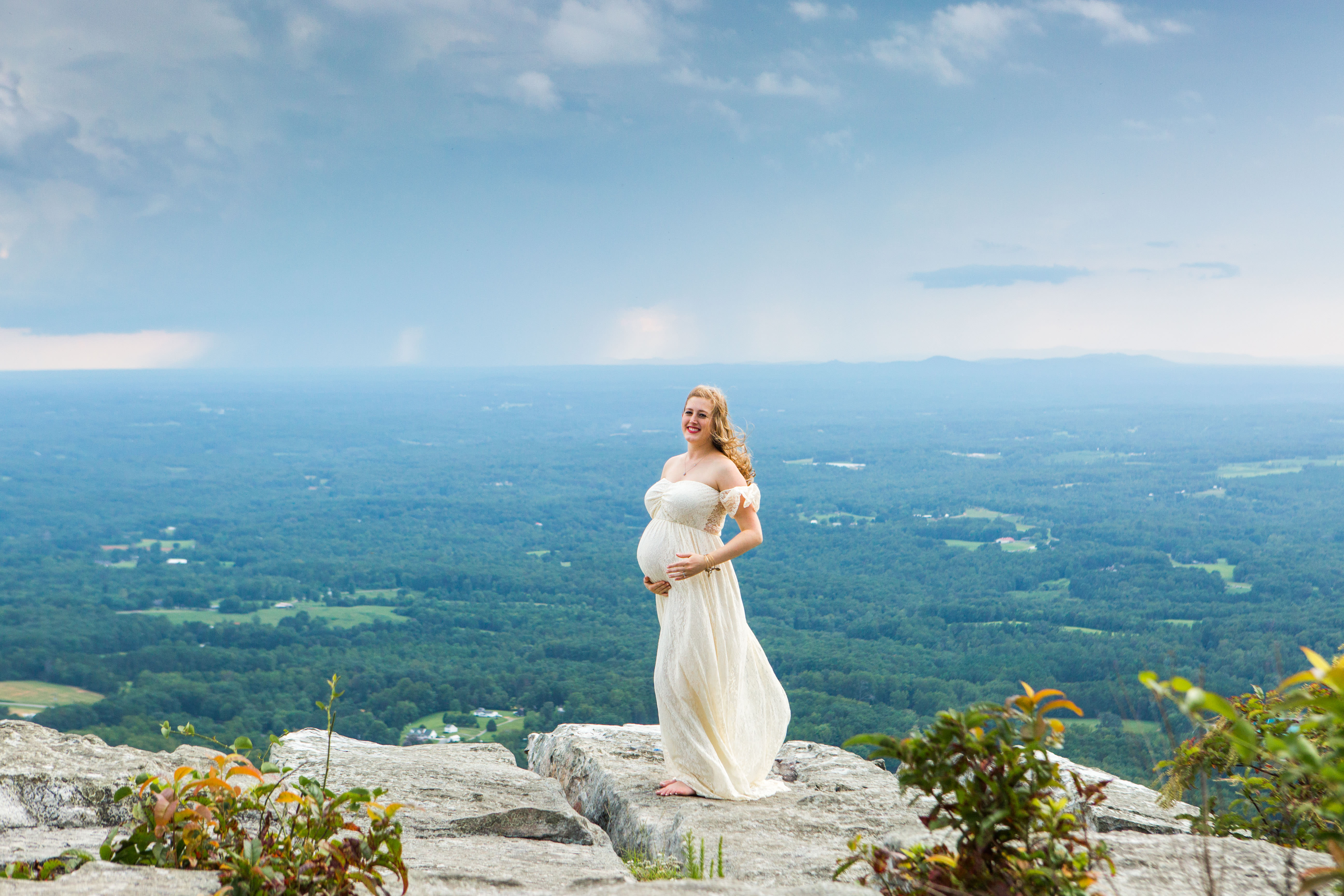 pregnant woman white maternity dress on ledge pilot mountain storm