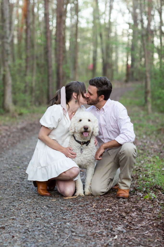 couple kissing while petting dog
