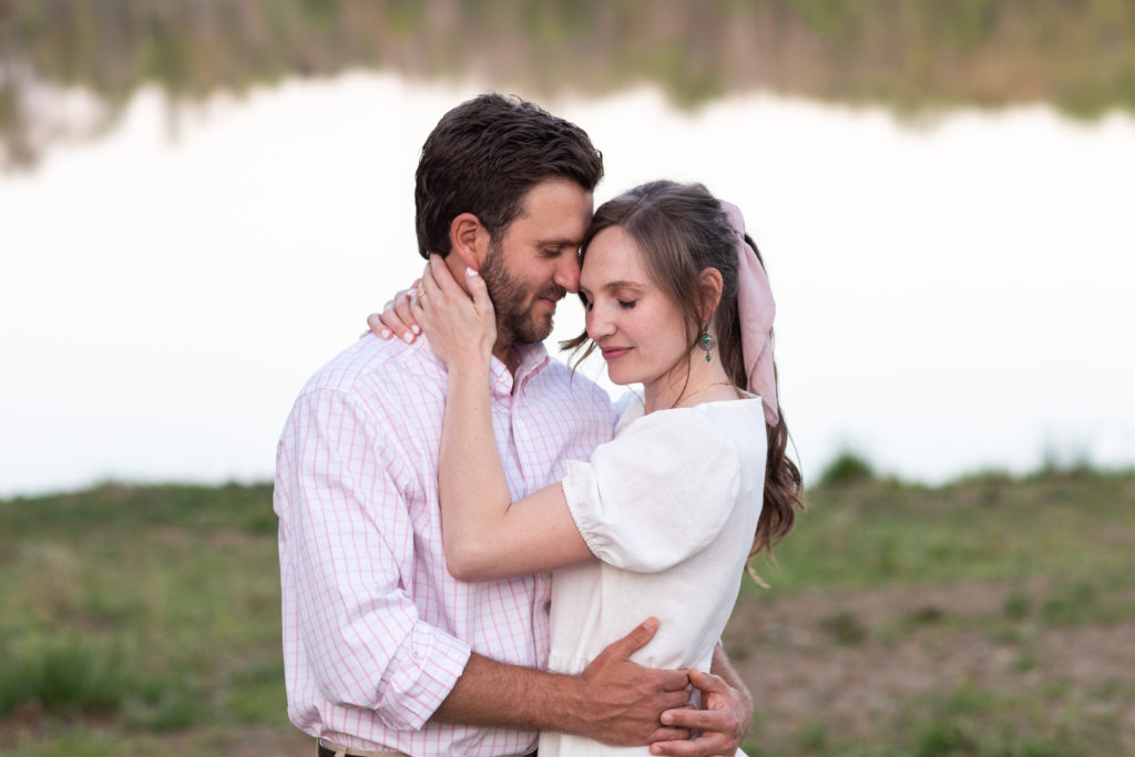 couple embracing with eyes closed in front of lake